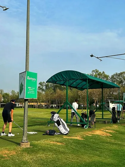A lone golfer practices from the mat, with his golf bag and a bucket of balls at the ready.