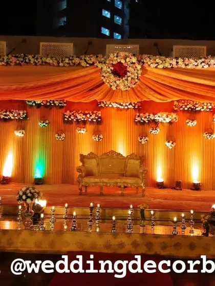 A classic stage decoration with a gold and peach color theme, featuring a royal sofa and warm uplighting.