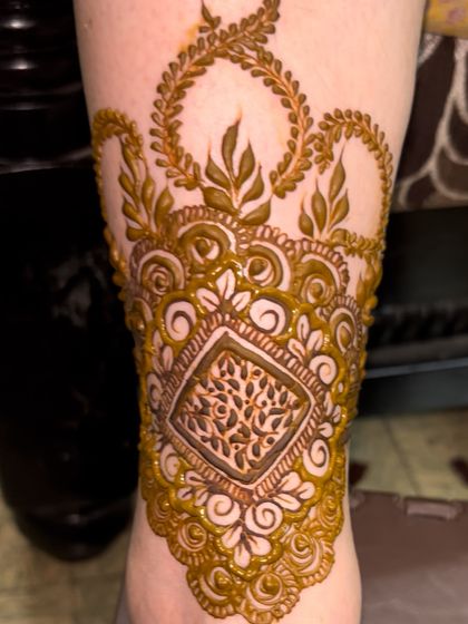 A close-up of the armband-style detail on the ankle. The design features a unique tree-of-life motif.