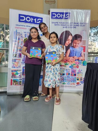 Two sisters proudly showing off the paintings they created. It is wonderful to see siblings sharing a creative hobby.