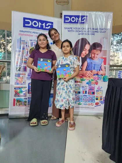 Two sisters proudly showing off the paintings they created. It is wonderful to see siblings sharing a creative hobby.