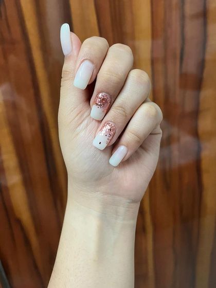 A clean and simple set of white square nails with a single accent nail in rose gold glitter.