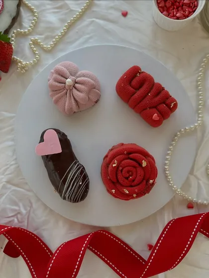 Decadent mini desserts crafted with love. This platter showcases our mini mousse cakes in various romantic shapes, including a rose, a heart, and the word 'LOVE'.