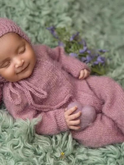 The sweetest dreams bring the sweetest smiles. I captured this moment of pure bliss with the baby dressed in a cozy, hand-knitted purple outfit, showcasing my gentle approach to posing sleeping newborns.