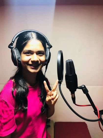 A student flashes a peace sign during her first studio recording session. It's a fun and exciting experience that builds confidence.