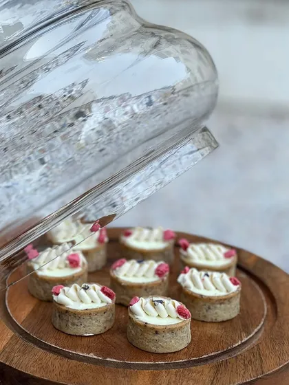 Delicate lemon tarts with a piped cream topping and a hint of berry. The tartness of the lemon is perfectly balanced by the sweet, buttery crust.