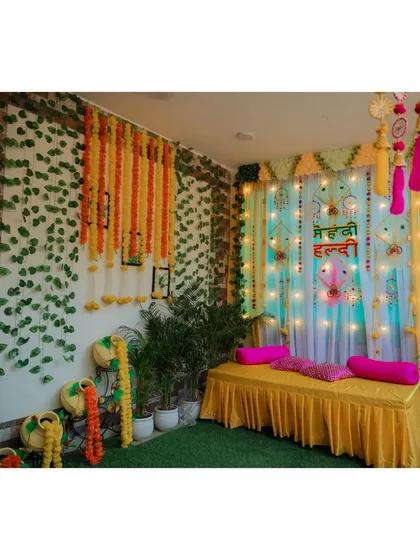 A wide shot of the vibrant and colorful decor for a home-based Mehndi and Haldi ceremony.