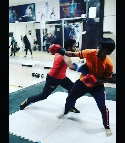 Two students engage in a controlled boxing sparring drill during an MMA class. This practice is essential for learning timing, distance management, and how to react under pressure.