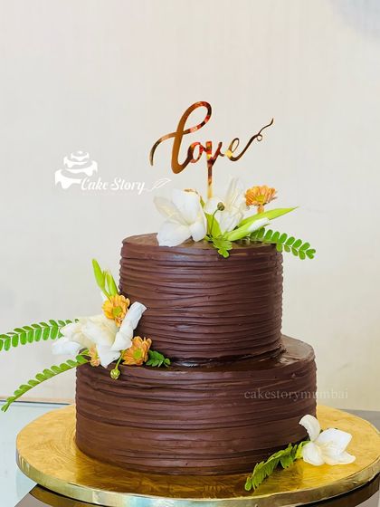 A rich, two-tier chocolate cake perfect for any celebration of love. The textured chocolate frosting is beautifully complemented by fresh, delicate flowers.