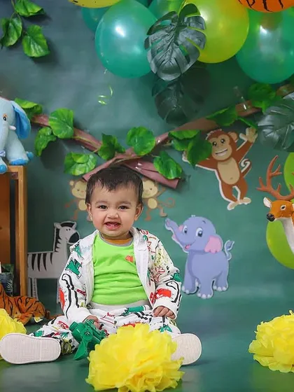 A happy little explorer in our jungle-themed studio setup. Surrounded by friendly animal props and lush greenery, he's ready for his wild first birthday adventure.