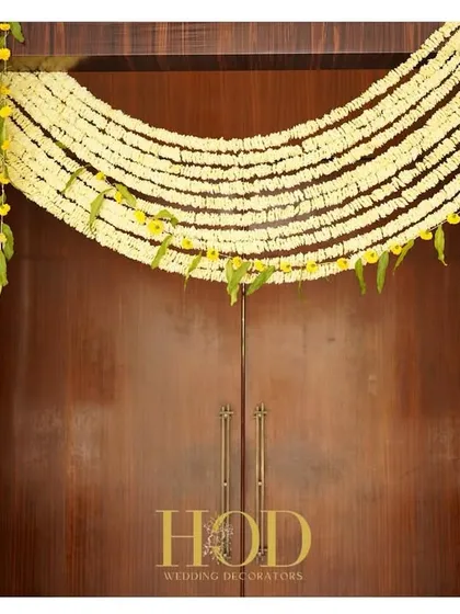 A simple yet elegant door decoration using strings of jasmine flowers, a classic and fragrant way to adorn an entrance for a traditional ceremony.