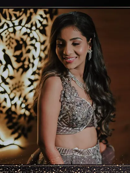 A close-up of the bride's Sangeet look against a beautifully lit background. Her soft waves and radiant makeup make her shine.