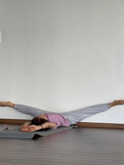 Using the wall to explore a deep split stretch, allowing gravity to help open the hips in a supported way.