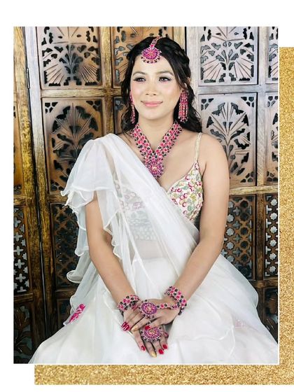 A seated view of our white and pink floral lehenga, paired with stunning pink jewellery for a complete, glamorous look.