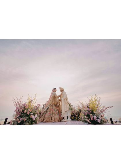 A serene beachside ceremony for Vedika and Yuvraj in Goa. The pastel sky and the gentle waves provide a tranquil and romantic setting for their vows.