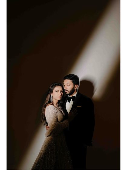 A classic, moody couple portrait. The single light source creates a dramatic, intimate feel, drawing all the attention to the couple's embrace and serene expressions on their engagement night.