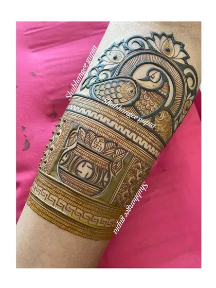 This arm band combines two auspicious motifs: a peacock and a kalash (a ceremonial pot). The use of bold lines and shading makes the design stand out clearly.