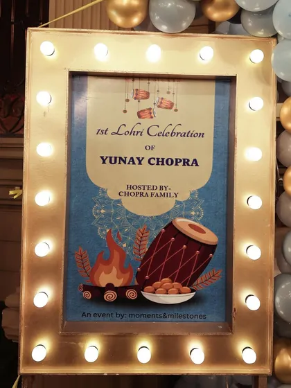 The welcome sign for the Lohri celebration, featuring traditional motifs like a dhol and bonfire.