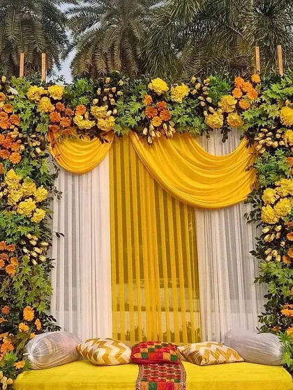 A beautiful floral arch using a mix of yellow and orange flowers with lush greenery. This kind of arch is perfect for an entrance or as a backdrop for an outdoor Haldi ceremony.
