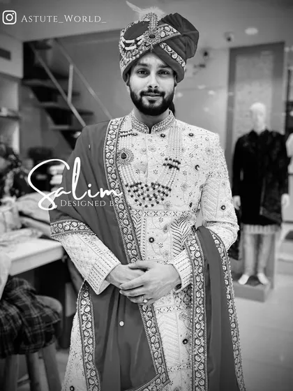 A black and white photo highlighting the texture and detail of this groom's sherwani. The outfit features mirror work and is paired with a traditional safa and a contrasting stole.