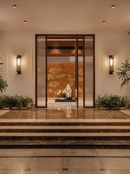 The entrance foyer of Mehalin Farm sets a tone of calm sophistication. A central sculpture is framed by a wooden portal, with marble steps and carefully placed plants guiding the transition from outside to inside.