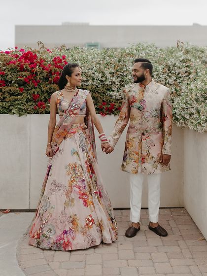 A moment of connection before the party begins. Their matching floral ensembles look stunning against the bougainvillea, showcasing our approach to vibrant, coordinated couple styling.
