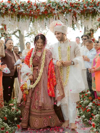 The couple walks together after their wedding ceremony, surrounded by family and a shower of petals. A perfect candid moment of happiness.