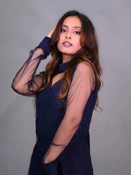 A model posing in a navy blue dress with sheer sleeves. The pose is elegant and ideal for a sophisticated fashion portfolio.