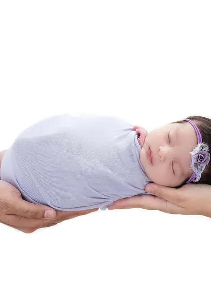 A classic newborn pose, with the baby held securely in the hands of both parents. This minimalist, high-key shot on a white background symbolizes the family's foundation of love and support for their new arrival.