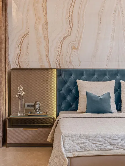 Detail is paramount in our designs. In this master bedroom, a headboard of rich teal velvet is set against a backdrop of Vanilla Onyx marble, with integrated brass accents providing a touch of warmth and opulence.