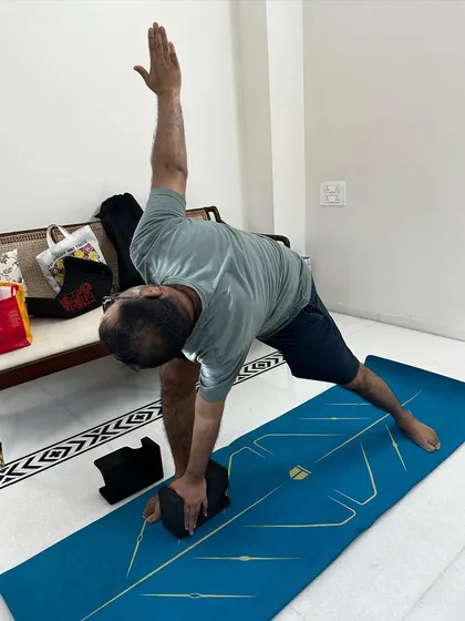 Using a block for support in Trikonasana (Triangle Pose). This modification helps maintain alignment while working around joint pain from gout.