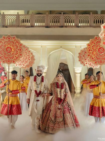The couple's grand exit, walking through a cloud of smoke while being escorted under traditional umbrellas.