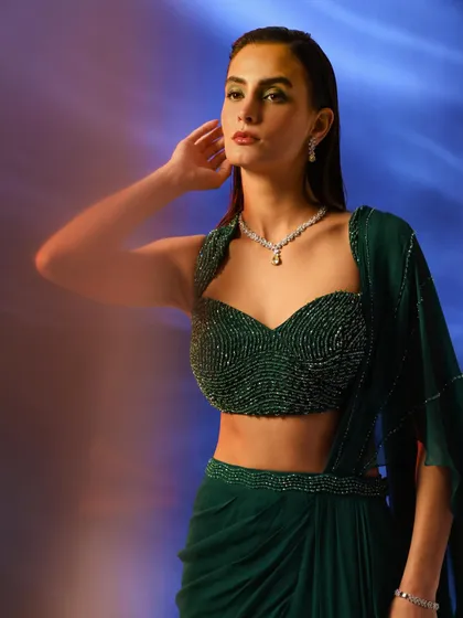 A model wearing a stunning emerald green beaded bustier and draped skirt. The diamond necklace adds a touch of luxury, making this a perfect look for a high-end jewelry collaboration.