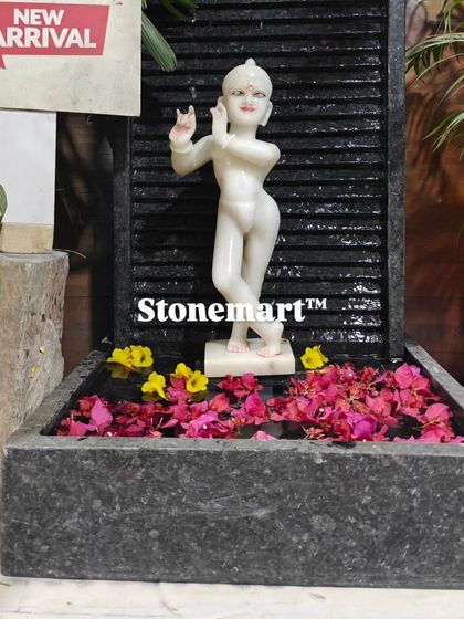 The Kanha Ji fountain decorated with floating flower petals. The contrast between the white marble, dark granite, and colorful flowers is stunning.