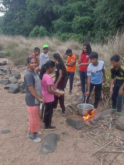 Campers learn the basics of outdoor cooking, preparing a meal over a campfire at the Barapole nature camp.
