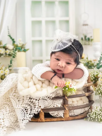 A precious awake moment! This baby peeks over the edge of a basket, surrounded by a beautiful arrangement of white and cream flowers.