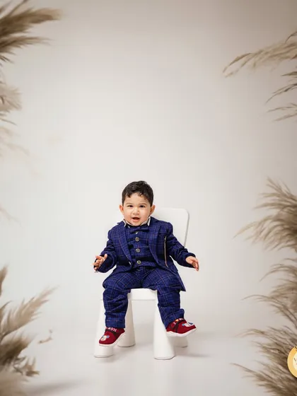 Dressed to impress in a tiny suit for his first birthday. This portrait uses a simple white background with pampas grass to create a sophisticated and modern look.
