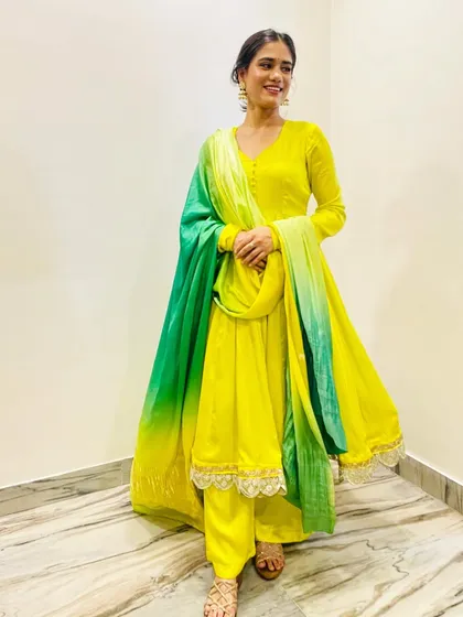 This lemonade yellow Anarkali set is perfect for a Haldi or Mehndi ceremony. The flowing silhouette and contrasting green dupatta create a look that is both joyful and effortlessly elegant.