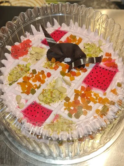 Here is another look at our Kulfi Falooda cake, packed and ready to go. You can see the rich toppings of pistachios, almonds, and colorful jellies that give it its signature taste and texture.