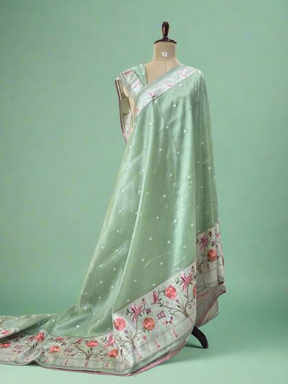 A lovely pastel green tissue saree with a detailed Paithani border featuring floral and bird motifs.