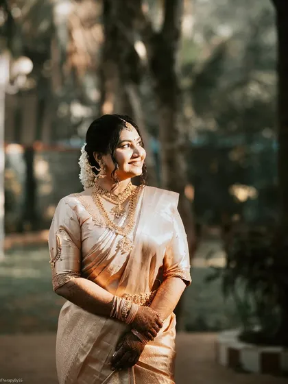 Golden hour glow capturing the essence of South Indian elegance. This bride is radiant in her cream and gold Kanjeevaram, her skin luminous in the warm light.