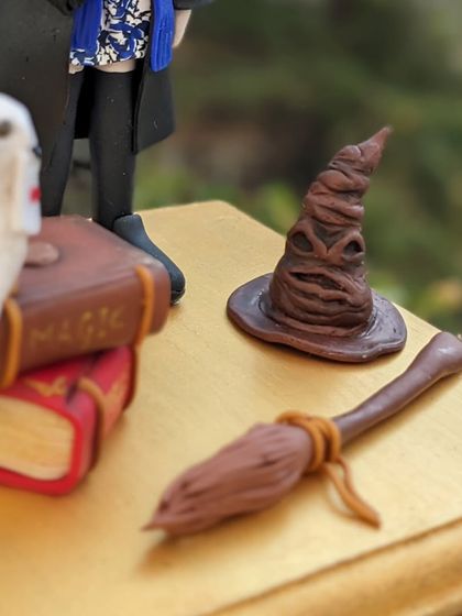 A close-up of the miniature sorting hat and broomstick from the Harry Potter cake topper. I love getting lost in these tiny, magical details.
