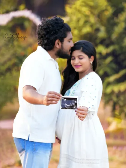 A sweet outdoor portrait of a couple holding their baby's ultrasound picture. The natural background and their loving expressions make this a deeply personal and meaningful shot.