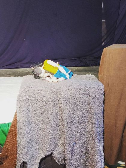 A puppet lies on the stage before a show begins. This quiet moment captures the anticipation and potential before the story starts.