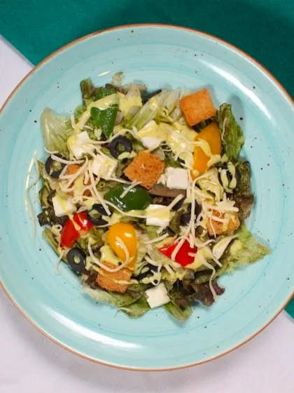 Our Caesar Salad is a refreshing choice, featuring crisp lettuce, crunchy croutons, olives, and bell peppers, all tossed in a creamy dressing and topped with cheese.