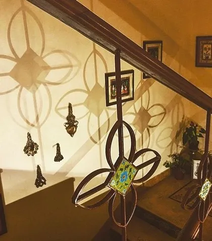 The custom-designed floral motif on this staircase railing at the Roopa Hariprasad Residence creates a dynamic play of light and shadow on the wall. This is an example of how we treat functional elements as opportunities for artistic expression in our residential architecture projects.