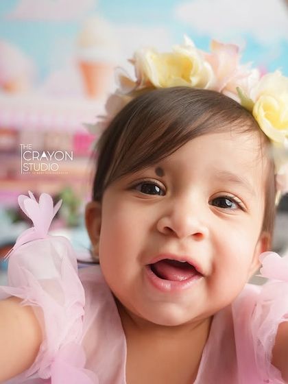 A joyful close-up of the birthday girl, reaching for the camera with a huge smile. This captures the playful and interactive nature of a one-year-old.