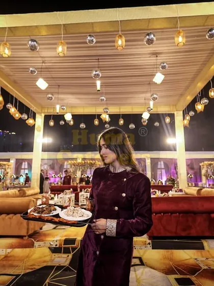 A member of my service staff carries a tray of appetizers through a grand, beautifully lit event space. My team is trained to navigate large crowds efficiently while providing attentive service.