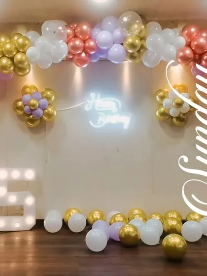 For a grand 75th birthday celebration, we created this wide backdrop with a beautiful pastel balloon arch. The setup includes large '75' marquee numbers and a central neon sign, perfect for a large stage in a banquet hall.