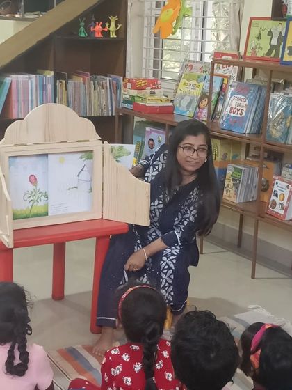 A storyteller smiles as she uses a Kamishibai story box. This unique prop is one of the special tools we use to make our sessions memorable and visually stimulating for the children.